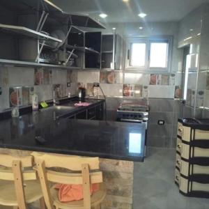 a kitchen with a black counter and two wooden chairs at الاسكندريه المعموره الشاطئ in Alexandria