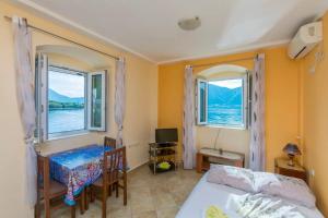 - une chambre avec un lit, une table et deux fenêtres dans l'établissement Apartments Mir i dobro, à Kotor