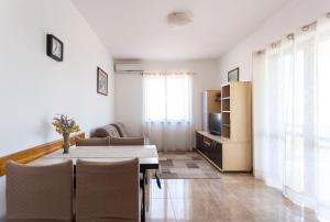 een woonkamer met een tafel en stoelen en een televisie bij Holiday home Milka - in center & close to the sea in Sali