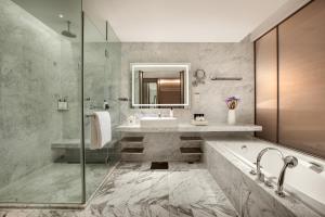 a bathroom with a tub and a sink and a mirror at InterContinental Beijing Beichen, an IHG Hotel in Beijing