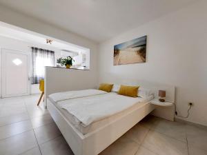 una camera da letto bianca con un grande letto bianco con cuscini gialli di Apartments Jordanka a Crikvenica