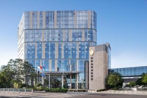 un edificio alto con un reloj delante en InterContinental Beijing Beichen, an IHG Hotel, en Beijing