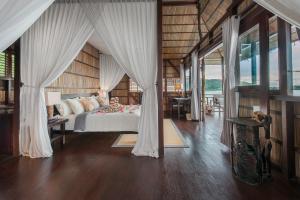 a bedroom with a bed with white drapes at Papua Paradise Eco Resort in Pulau Birie