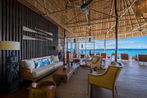 una sala de estar con sofá y sillas y el océano en Papua Paradise Eco Resort, en Pulau Birie