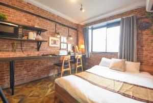 a bedroom with a brick wall with a bed and a desk at Comfy Stay Sakuramachi in Nara