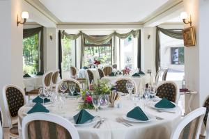 ein Esszimmer mit weißen Tischen, Stühlen und Fenstern in der Unterkunft Sungarden Golf & Spa Resort in Cluj-Napoca