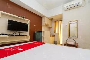 1 dormitorio con 1 cama y TV en la pared en RedLiving Apartemen Green Lake View Ciputat - Pelangi Rooms 1 Tower E, en Pondokcabe Hilir