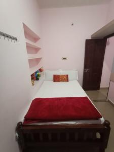 a bedroom with a bed with a red blanket on it at Nakshatra Homestay in Madikeri