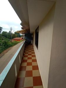 a corridor of a building with a checkerboard floor at Nakshatra Homestay in Madikeri