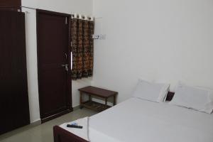 Un dormitorio con una gran cama blanca y una puerta en Agp Homestay en Chennai