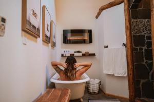 a woman sitting in a bath tub in a bathroom at Yosemite Charm by Casa Oso with spa and breathtaking views in Mariposa