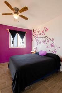 - une chambre avec un lit noir et un mur violet dans l'établissement Villas del Sol, à Ipala