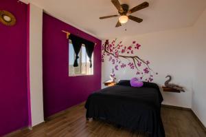 1 dormitorio con paredes de color púrpura y ventilador de techo en Villas del Sol, en Ipala