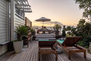 a deck with chairs and a table and an umbrella at The Lofts Boutique Hotel in Knysna