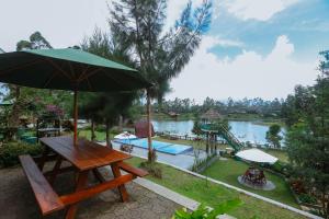 une table de pique-nique avec un parasol au bord d'une rivière dans l'établissement De Bloem Lake View Pangalengan, à Pengalongan