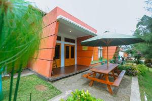 a patio with a wooden table and an umbrella at De Bloem Lake View Pangalengan in Pengalongan