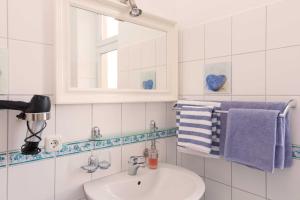bagno con lavandino, specchio e asciugamani di Pension Arielle _ Objekt 28014 a Warnemünde