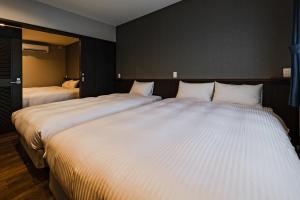 2 Betten in einem Hotelzimmer mit 2 in der Unterkunft Ahman Inn Island Yagaji in Nago