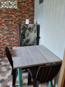 einen Holztisch mit zwei Stühlen neben einer Ziegelwand in der Unterkunft Homey Place with Garden view in Puerto Princesa