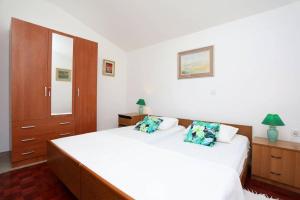 um quarto com uma grande cama branca e armários de madeira em Apartments Nada em Rabac