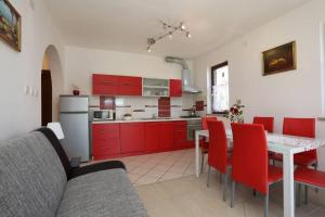 uma cozinha com armários vermelhos e uma mesa com cadeiras vermelhas em Apartments Nada em Rabac