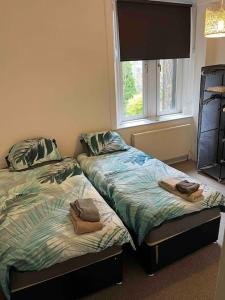 two beds sitting next to each other in a bedroom at Centrally located 1 bed flat with furnishings & white goods. in Gourock