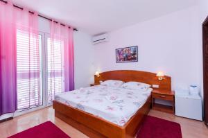 a bedroom with a bed and a desk and windows at Rooms Mladen P in Banjol