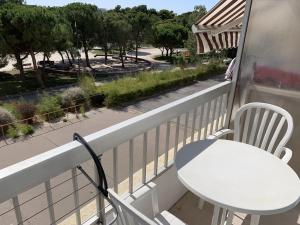 a white table and chair on a balcony with a view of a park at T1 Classé 3 Étoiles avec Animaux Admis et Climatisation - FR-1-571-49 in Balaruc-les-Bains +2 photos