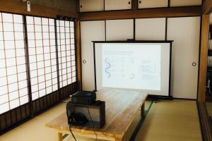 a projection screen in a room with a table and a projector at Worcation base Kaminyu Yamane House - Vacation STAY 03960v in Nagahama
