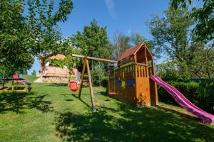 einen Kinderspielplatz mit Rutsche und Schaukel in der Unterkunft Rustic Cottage With Heated Pool - Happy Rentals in Velika Buna