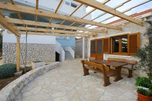 a patio with a wooden bench and a pergola at House Lavanda in Premuda