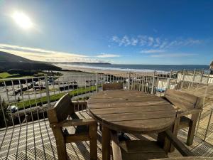 einen Holztisch und Stühle auf einem Balkon mit Meerblick in der Unterkunft Southover Beach in Woolacombe