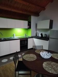 een keuken met een tafel en stoelen en een groene muur bij IL VICOLO_Carinissimo appartamento in centro storico, zona giorno mansardata in Belluno