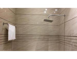 a bathroom with a shower with a white towel at Hotel Mrg Inn, Sri Ganganagar in Gangānagar