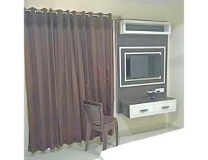 a room with a television and a chair and a window at Hotel Mrg Inn, Sri Ganganagar in Gangānagar