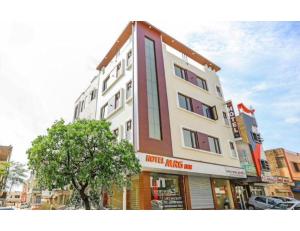 un edificio alto con un árbol delante de él en Hotel Mrg Inn, Sri Ganganagar, en Gangānagar