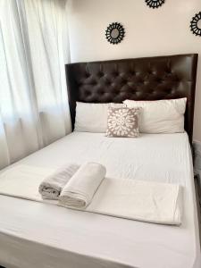 a white bed with a black headboard and white pillows at The Persimmon Studios Near Ayala and SM City Cebu in Cebu City