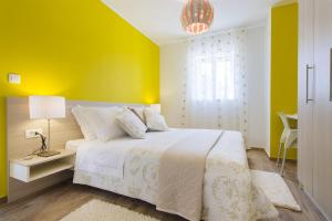 a bedroom with a white bed and a yellow wall at Villa Burica in Vinišće +24 photos