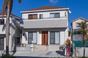 a white house with a tree in front of it at Y's沖縄リゾートベースNo.1 in Onna