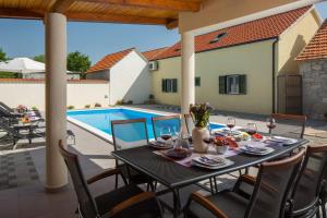 a patio with a table and chairs and a swimming pool at Villa Giardino in Drniš