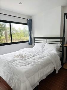 a bedroom with a white bed with a window at Dm-udon (ดีเอ็ม อุดรธานี) in Udon Thani