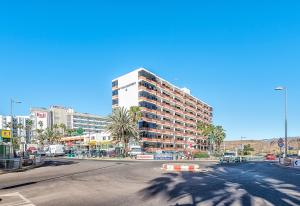a large building on a city street with palm trees at APARTAMENTO a PIE del MAR in Playa del Ingles