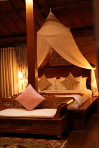 2 camas en una habitación con cama con dosel en Pondok Sugara, en Tampaksiring