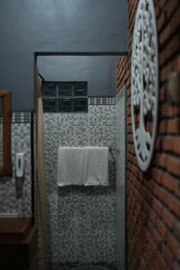 y baño con ducha, toallas y pared de ladrillo. en Pondok Sugara, en Tampaksiring