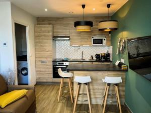 a kitchen with a couch and stools in a room at Apt RDC avec sa terrasse privée in Saint Malo