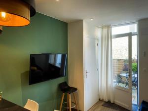 a living room with a television on a green wall at Apt RDC avec sa terrasse privée in Saint Malo