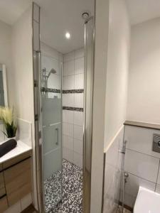 La salle de bains est pourvue d'une douche avec une porte en verre. dans l'établissement Apt RDC avec sa terrasse privée, à Saint-Malo