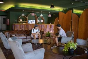 two people sitting on couches in a room with surfboards at Selina Montevideo in Montevideo