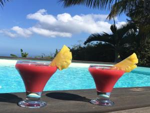 two cocktails sitting on a table next to a pool at La case Tori in Saint-Leu