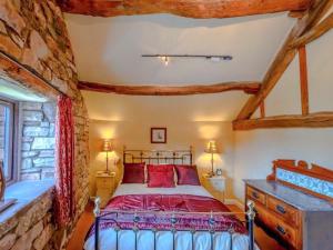 a bedroom with a bed and a stone wall at Lilac Barn in Newton Reigny